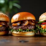 A variety of gourmet burgers including beef, venison, and salmon burgers on a rustic wooden table.