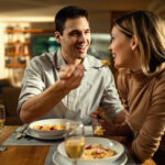 A couple sharing a romantic dinner at home, with wine glasses, candlelight, and a cozy atmosphere.