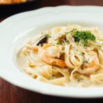 Creamy fettuccine Alfredo sauce recipe served on an elegant plate in a luxury restaurant setting